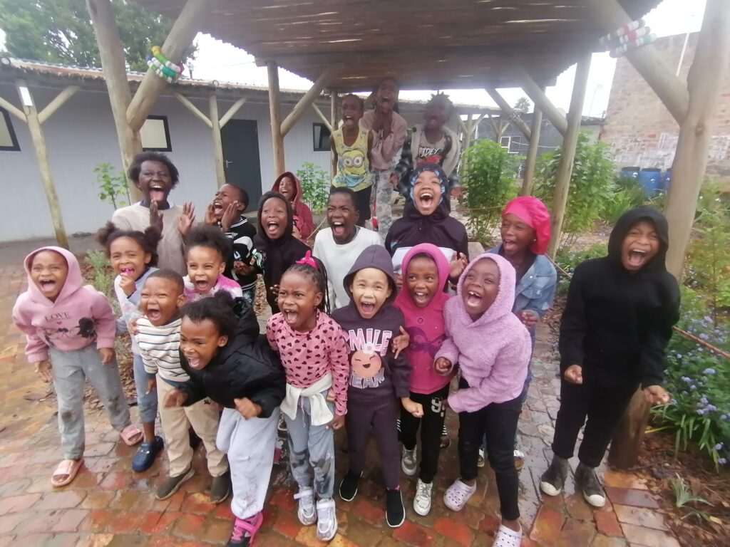 A big group of children laughing and pulling faces for the camera