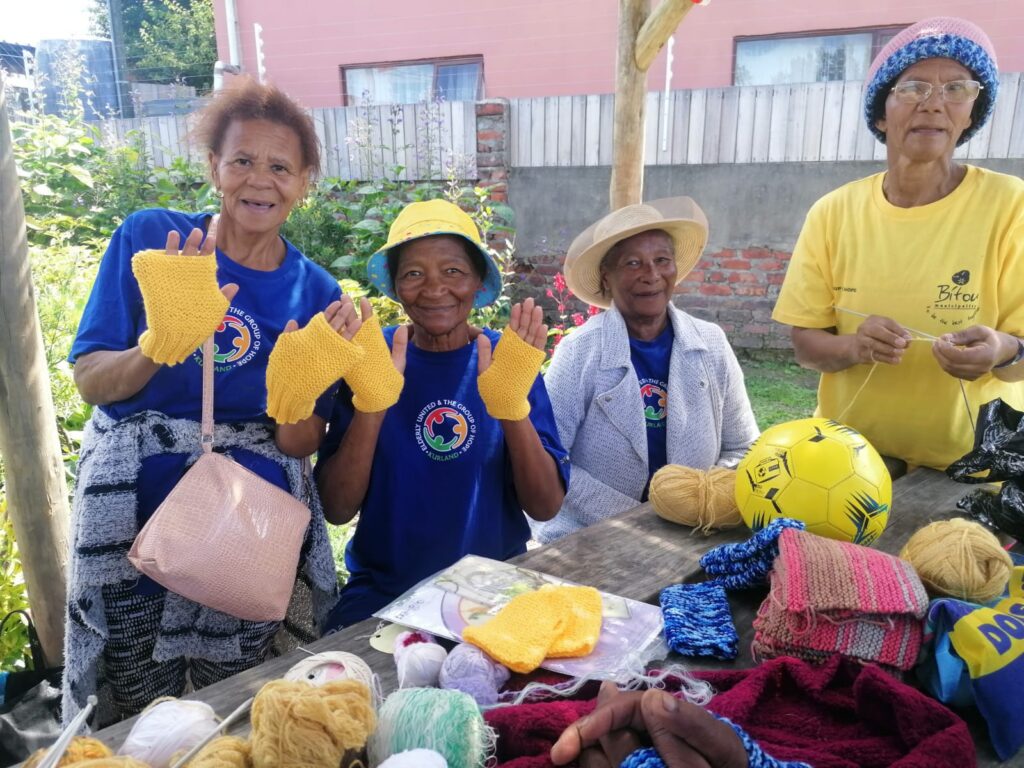 Community Care participants displaying knitted items during a group activity