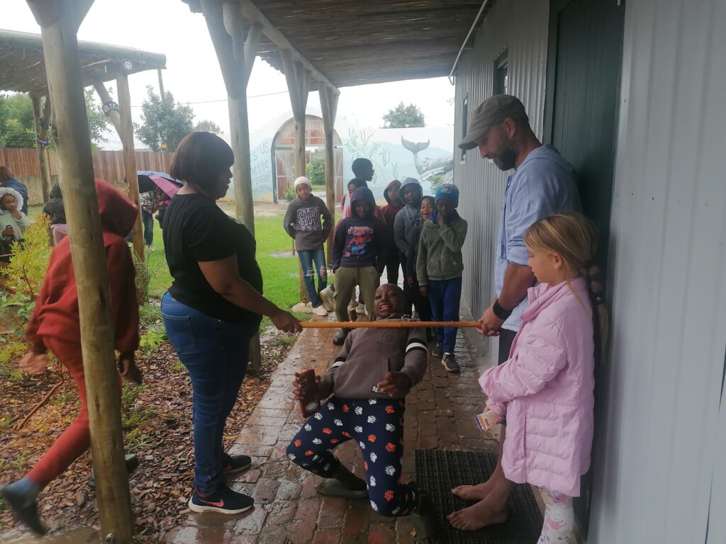 Children playing a limbo game under the centre’s veranda