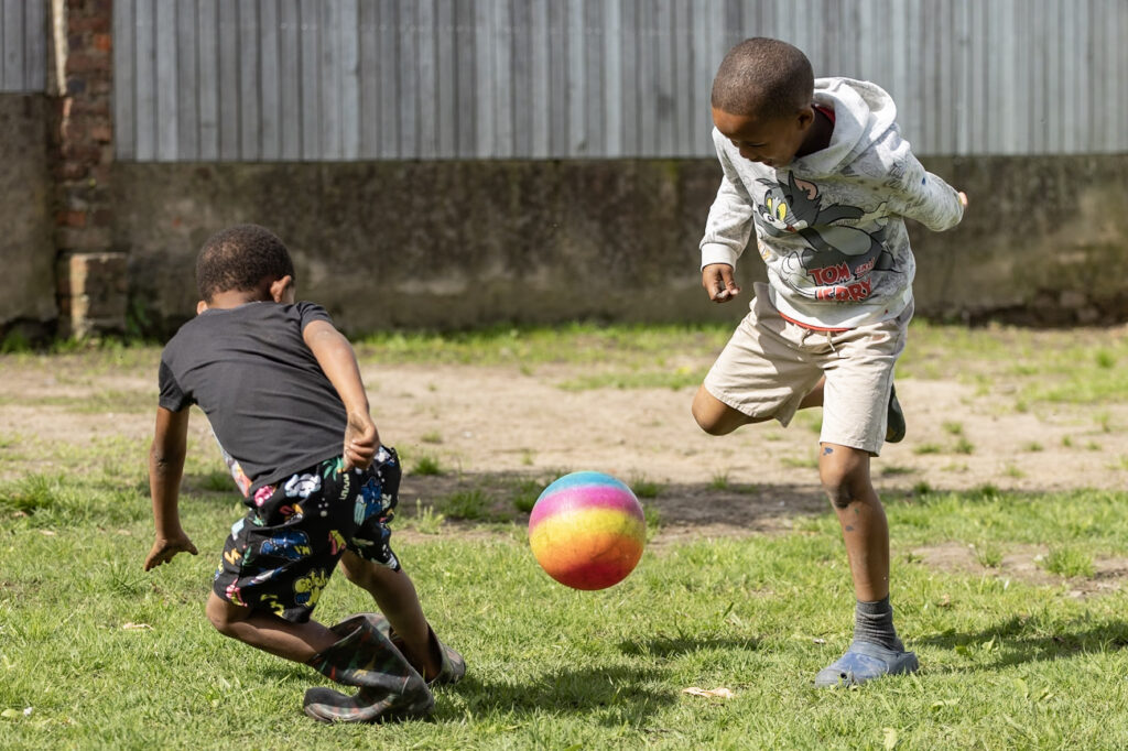 Two boys playing with a colourful ball on the grass