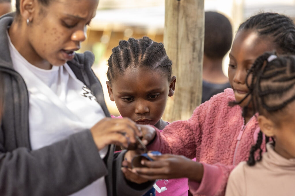 A young facilitator helping girls with a hands-on craft activity