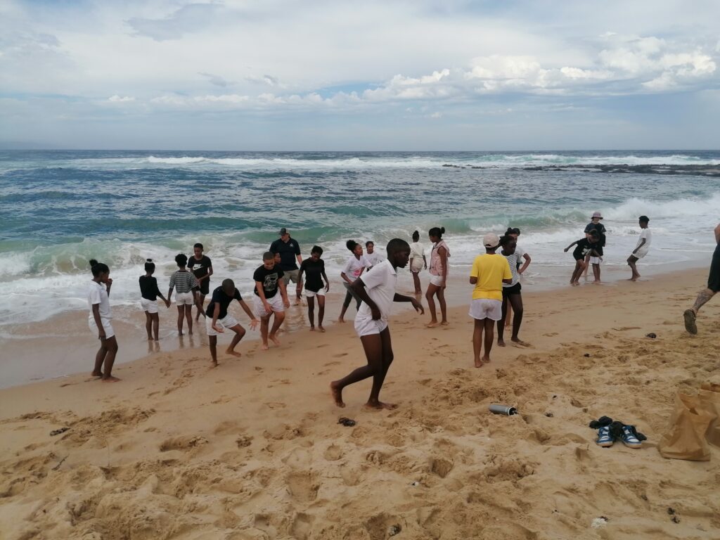 A group of children playing on the beach beside the waves