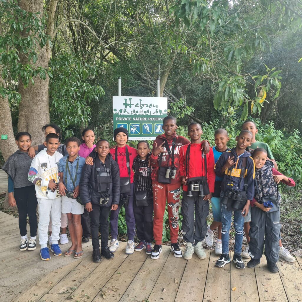A group of children on a boardwalk beside a private nature reserve sign